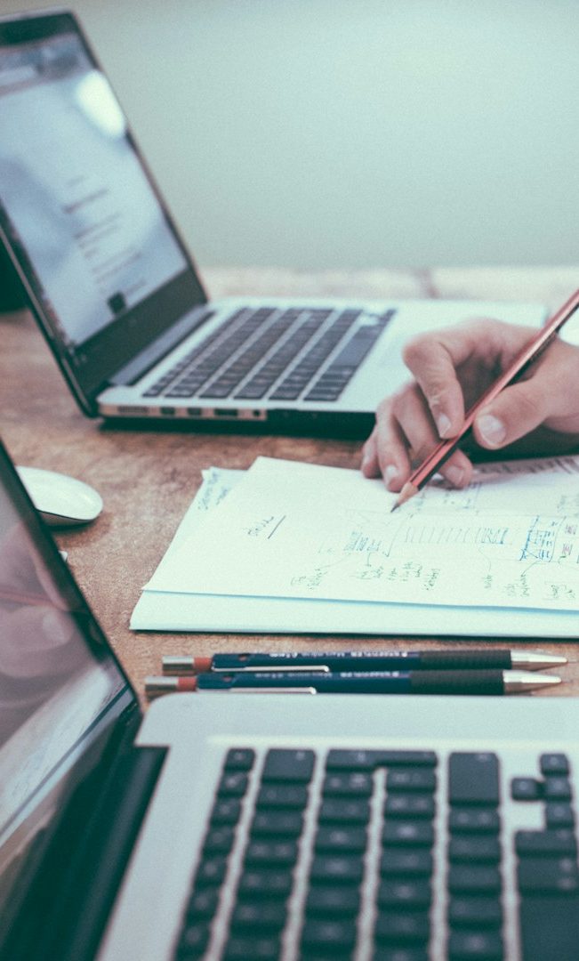 Mano colocando una caja en una cinta transportadora en un almacén lleno de estanterías.